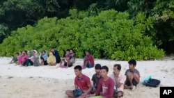 A photo taken July 26, 2020, by the Malaysian Maritime Enforcement Agency, shows Rohingya refugees, who were thought to have drowned, sitting on a beach on Rebak Island, off the resort island of Langkawi, Malaysia.