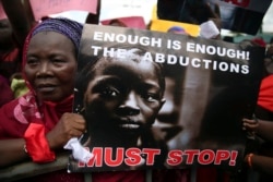FILE - A woman holds a sign during a protest demanding the release of abducted secondary school girls from the remote village of Chibok, in Lagos, May 5, 2014.