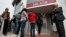 People queue up to make a transaction at an ATM outside a branch of Laiki Bank in Nicosia, March 21, 2013. 