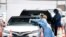 FILE - Health care workers prepare to test drivers at a drive-through coronavirus testing site outside of Hard Rock Stadium, June 26, 2020, in Miami Gardens, Florida.