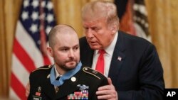 President Donald Trump leans in after presenting the Congressional Medal of Honor to former Army Staff Sgt. Ronald J. Shurer II for actions in Afghanistan, in the East Room of the White House, Oct. 1, 2018, in Washington. 