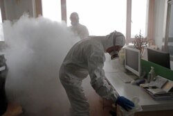 Workers with sanitizing equipment disinfect an office following an outbreak of the coronavirus in the country, in Shanghai, China, Feb. 12, 2020.