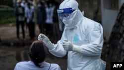 A health worker in Personal Protective Equipment (PPE) suit collects a swab samples from a man to test for the Covid-19 coronavirus at the department of medical research (DMR) in Yangon on October 8, 2020. (Photo by Ye Aung Thu / AFP)