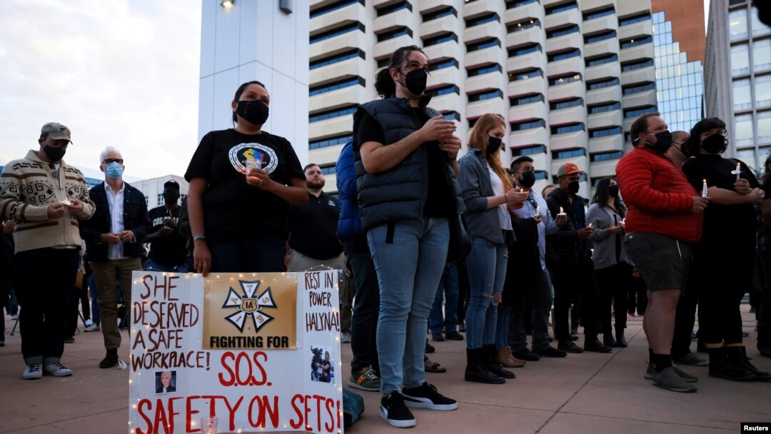 A woman displays a sign calling for workplace safety at a vigil for cinematographer Halyna Hutchins, who died after being shot by Alec Baldwin on the set of his movie "Rust", in Albuquerque, New Mexico, October 23, 2021. 