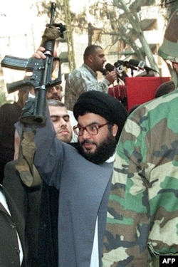 FILE - Lebanon's Hezbollah Secretary General Sayyed Hassan Nasrallah brandishes an Israeli machine-gun offered to him by a Hezbollah militant during a rally in Beirut on May 17, 1999, after Hezbollah fighters attacked a post of Israel's proxy militia, the South Lebanon Army.