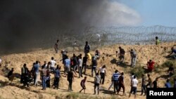 Manifestants palestiniens lapidant des soldats israéliens après des protestations contre le blocus de la bande de Gaza, à la frontière entre ce territoire et Israel, le 19 mai 2017. 