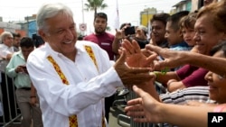 FILE - Presidential hopeful and two-time candidate Andres Manuel Lopez Obrador greets supporters as he arrives at a campaign rally for Delfina Gomez, who is running for Mexico state governor with his National Regeneration Movement, or MORENA, in Nezahualcoyotl, Mexico state, May 28, 2017.