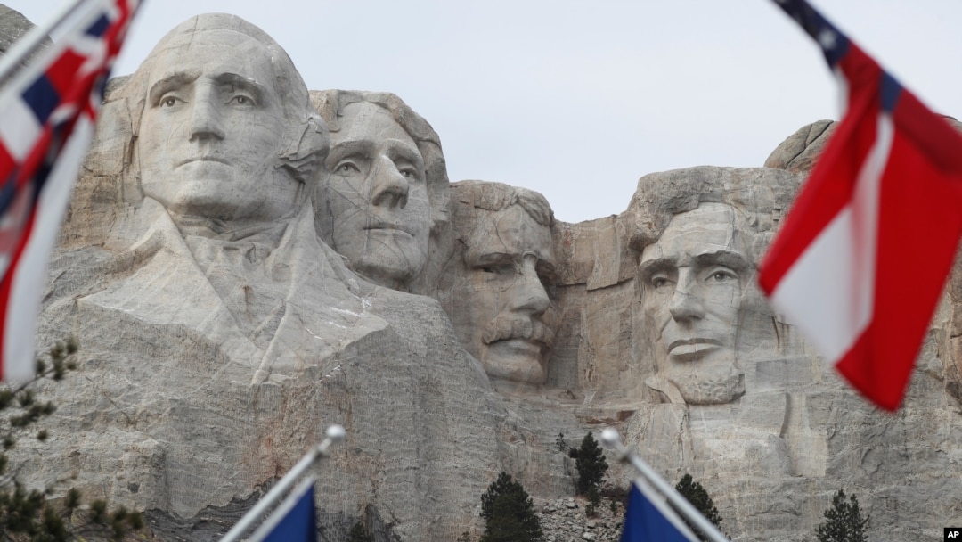 FILE - Flags frame the presidents on the Mount Rushmore monument near Keystone, South Dakota.