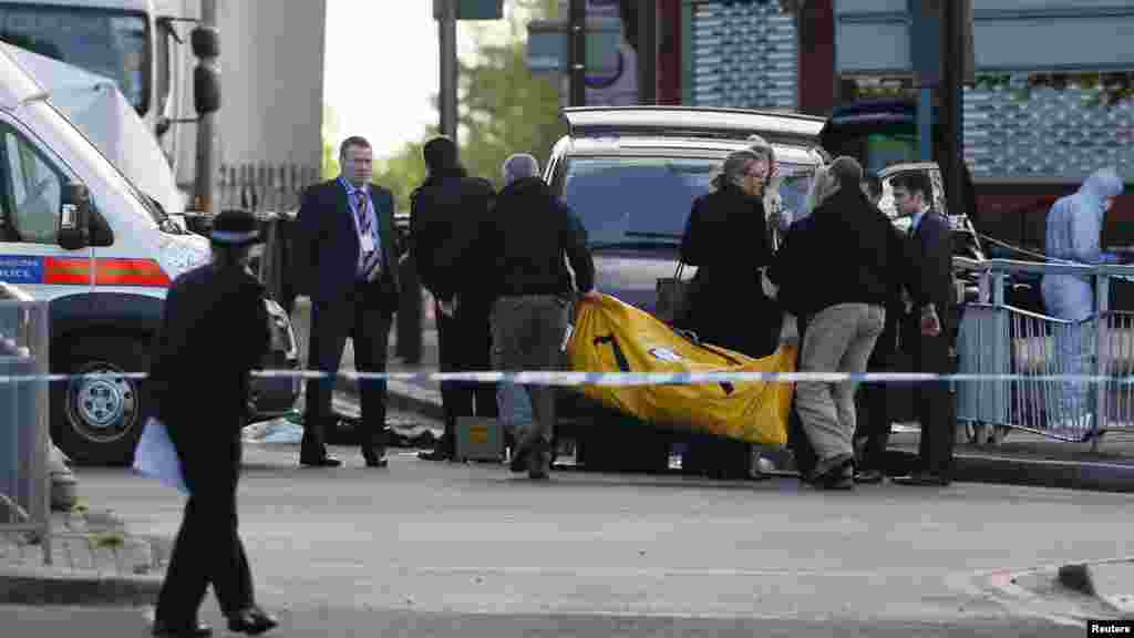 Police officers carry equipment while investigating a crime scene where one man was killed in Woolwich, southeast London May 22, 2013.