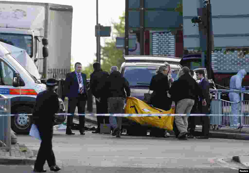 Police officers carry equipment while investigating a crime scene where one man was killed in Woolwich, southeast London May 22, 2013.