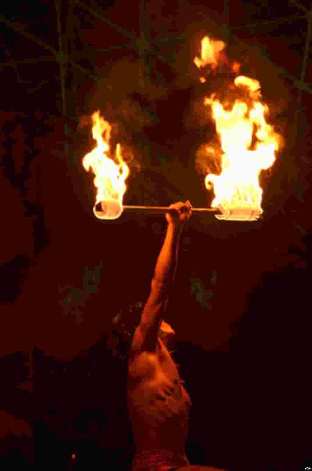 Besides hula dancers the resort's Polynesian-themed shows also feature local young men trained to perform with fire, (Steve Herman/VOA)