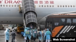 接載港人從武漢撤離的包機3月4日下午返抵香港國際機場。機上港人離開飛機後隨即在身著保護衣的工作人員指示下登上專車前往隔離營。（香港政府新聞處） 