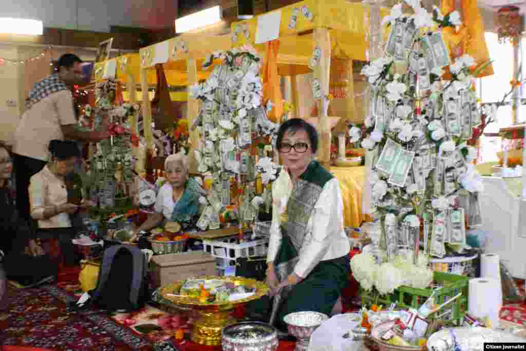 ທ່ານນາງ ອຸ່ນເຮືອນ ປະຖັມມະວົງ ຕາໂນວັນ ເຈົ້າພາບ ກໍາລັງນັ່ງຢູ່ຕໍ່ໜ້າກອງອັດທະ ສາມກອງ