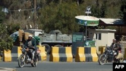 Yemeni men drive motorbikes past concrete blocks put in place outside the U.S. embassy in the capital Sanaa, Jan. 27, 2015. 