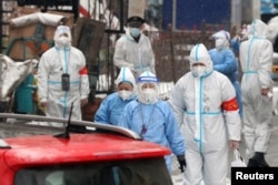 2022年3月14日，中国吉林省长春市新冠肺炎疫情爆发后，身着防护服的医务人员在雪地中行走，进入被封锁的住宅小区进行核酸检测