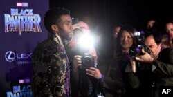 Chadwick Boseman, a cast member in "Black Panther," is trailed by photographers as he poses at the premiere of the film at The Dolby Theatre on Monday, Jan. 29, 2018, in Los Angeles. (Photo by Chris Pizzello/Invision/AP)