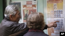 A Chinese couple look at a newspaper reporting on new General Secretary of Communist Party of China Xi Jinping and other members of the party leadership in Beijing, China, Nov. 16, 2012. 