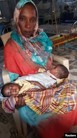 FILE - Sudanese refugee Fatma Ibrahim, who fled violence in the city of Nyala, South Darfur, holds her twin babies, Jana and Janat, at a health center at the Kalma camp in South Darfur, Sudan, on Feb. 18, 2024.