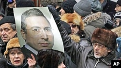 Supporters of Mikhail Khodorkovsky hold his portrait outside a court room in Moscow, 27 Dec 2010
