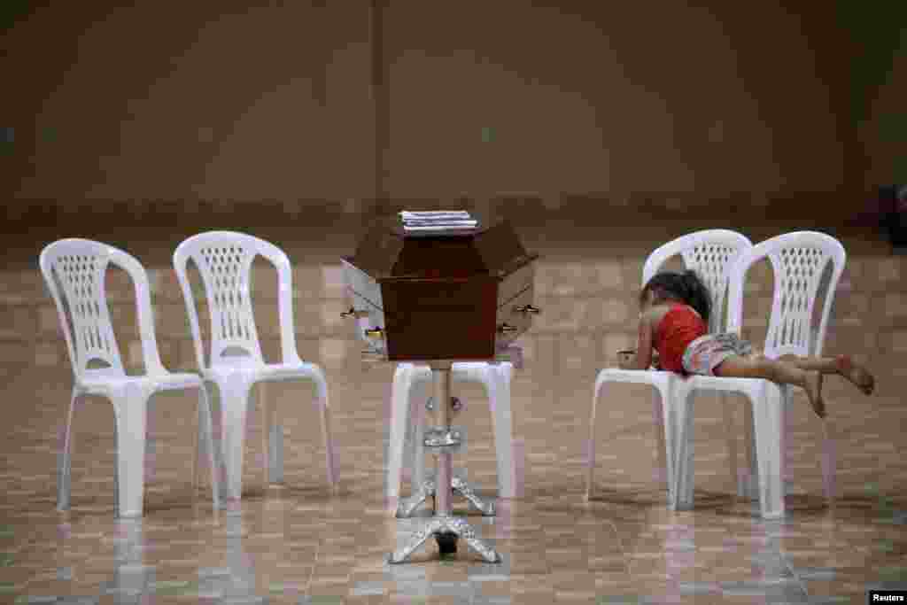 A relative of murdered prisoner, lies on a chair next to his coffin during a wake after a prison riot in the city of Altamira, Para state, Brazil, July 30, 2019.