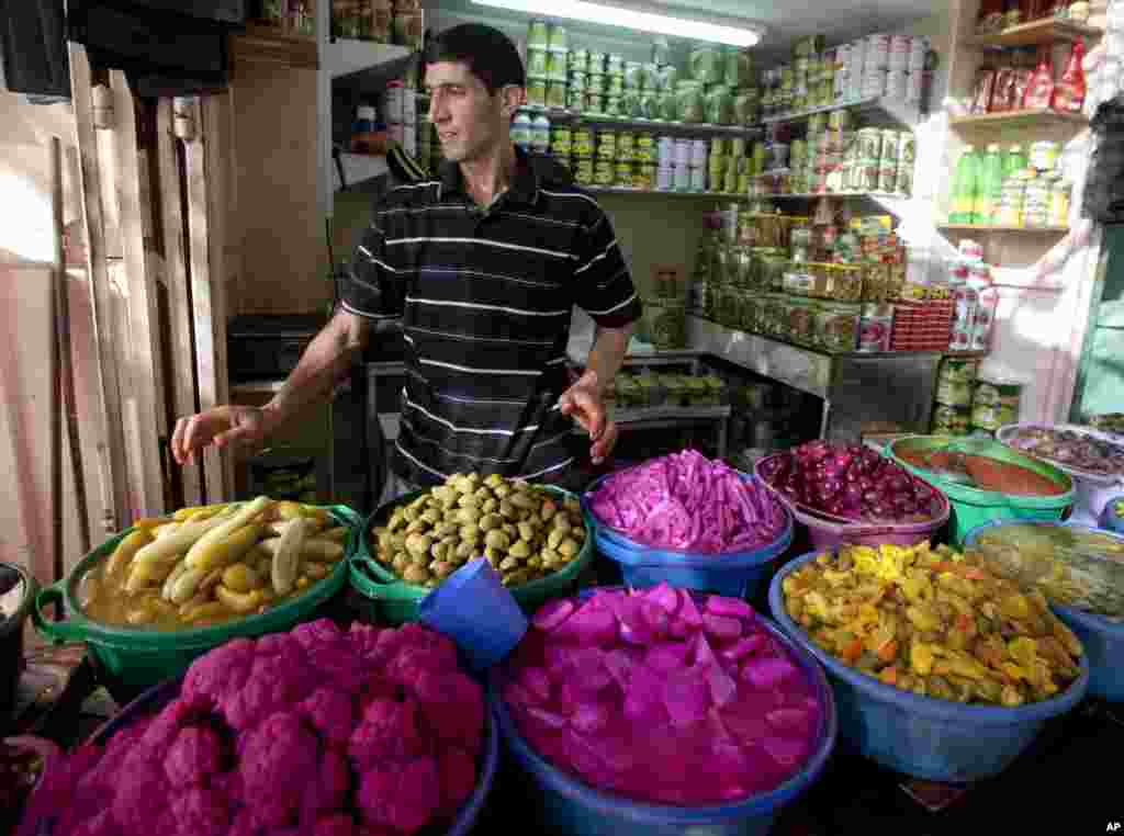 Seorang pedagang makanan di Palestina menjual acar sayuran dan buah zaitun menjelang Ramadan di sebuah pasar di Hebron, Tepi Barat (28/6). (AP/Majdi Mohammed)