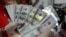 FILE - A worker counts U.S. dollar bills, which at currency exchange.