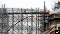 Workers walk through a scaffolding at Notre Dame cathedral, July 10, 2020 in Paris. Notre Dame Cathedral will be rebuilt just the way it stood before last year's devastating fire.