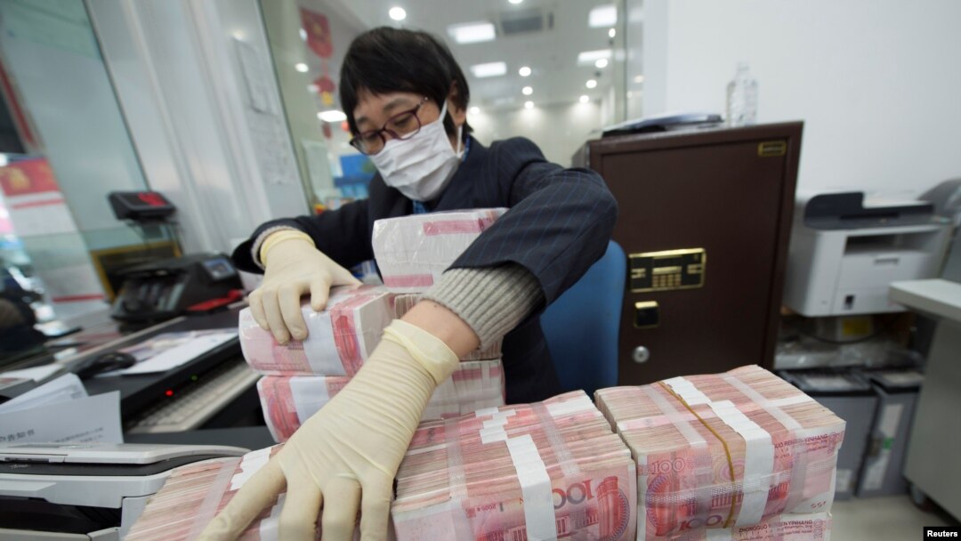 中国江苏省南通市一家银行的职员戴着口罩整理人民币钞票（2020年1月30日）