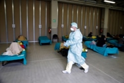 Patients lie on beds as a doctor walks past them, at a one of the emergency structures that were set up to ease procedures at the Brescia hospital, northern Italy, March 12, 2020.