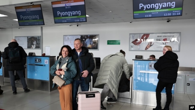 Sepasang suami dan istri Rusia berfoto setelah lapor masuk untuk menaiki pesawat ke Korea Utara di bandara internasional di Vladivostok, Rusia, 9 Februari 2024. (Foto: AP Photo)