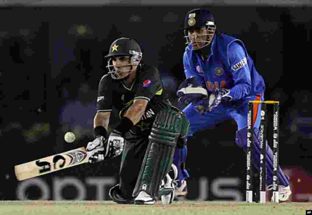 Pakistan's Misbah-ul-Haq (L) plays a shot as India's captain and wicketkeeper Mahendra Singh Dhoni watches, Mohali, India, March 30, 2011.