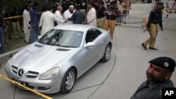 Police and security officials keep guard near the cordoned off vehicle of Shahbaz Taseer after he was kidnapped by unidentified men in Lahore, Aug. 26, 2011.