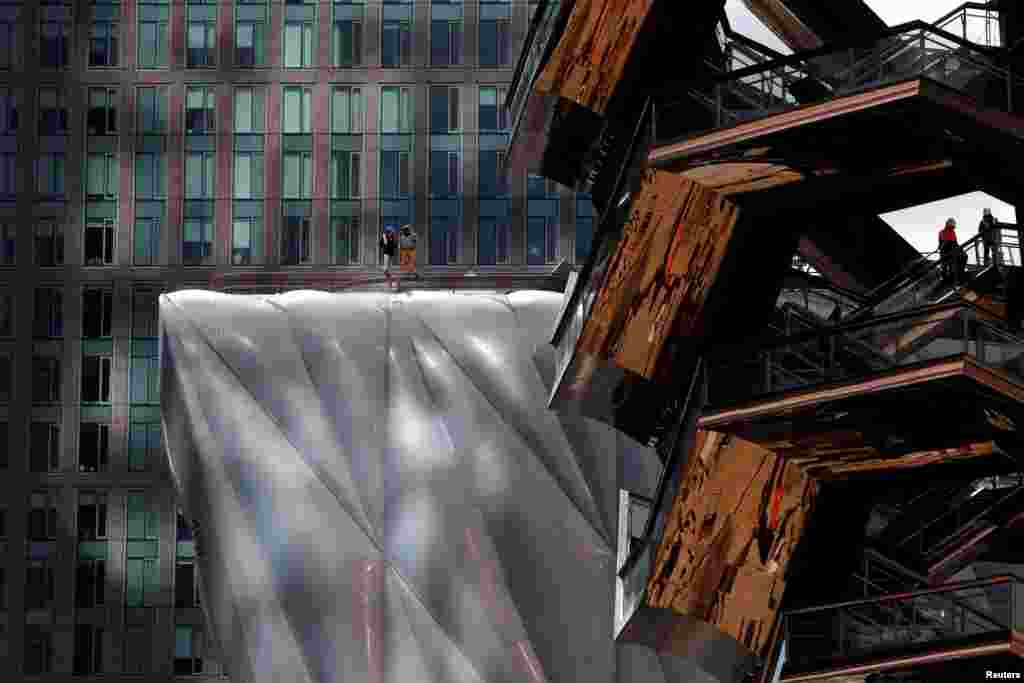 Workers are seen on &#39;The Vessel&#39; (R) comprised of 154&nbsp; connected flights of stairs and 80 landings designed by Thomas Heatherwick and on &#39;The Shed&#39; arts center (L) at the Hudson Yards development on Manhattan&#39;s West side, in New York City, New York, U.S., March 12, 2019.