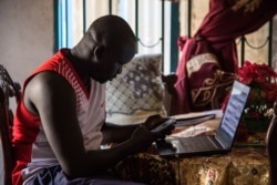 Junior Dau, 31, looks at photos of his cousin, who was killed in South Sudan's civil war, in Juba, South Sudan. (Chika Oduah/VOA)