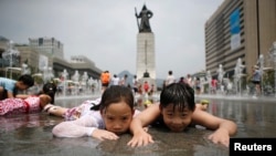 Anak-anak bermain di air terjun di tengah udara musim panas di Gwanghwamun, Seoul, Juli 2014. (Reuters/Kim Hong-Ji)