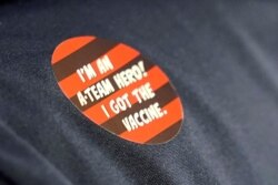 A worker at Queen Anne Healthcare, a skilled nursing and rehabilitation facility in Seattle, Washington, wears a celebratory sticker after receiving the Pfizer vaccination for COVID-19, Jan. 8, 2021.