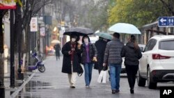 People wearing face masks to help protect against COVID-19 walk down an alley in Wuhan in central China's Hubei Province, Jan. 22, 2022. Sunday will mark two years since the city was placed under a 76-day lockdown to contain the first major outbreak of the coronavirus pandemic.