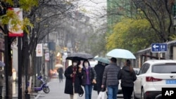 People wearing face masks to help protect against COVID-19 walk down an alley in Wuhan in central China's Hubei Province, Jan. 22, 2022. Sunday will mark two years since the city was placed under a 76-day lockdown as China tried to contain the first major