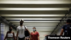 People wear masks as they pass through a pedestrian subway as cases of the infectious coronavirus Delta variant continue to rise in New York City, New York