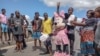 Manifestantes seguram uma reprodução uma boneca da personagem da Disney, Minnie Mouse, enquanto se concentram junto a uma portagem bloqueada da autoestrada que liga a capital moçambicana, Maputo, ao seu maior subúrbio, Matola, a 23 de janeiro de 2025. 