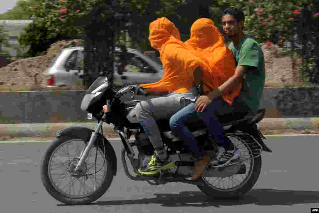 Dua pria India mengendarai motor sambil menutupi kepala mereka akibat udara panas yang menyengat di kota Amritsar yang mencapai 47 Celcius.