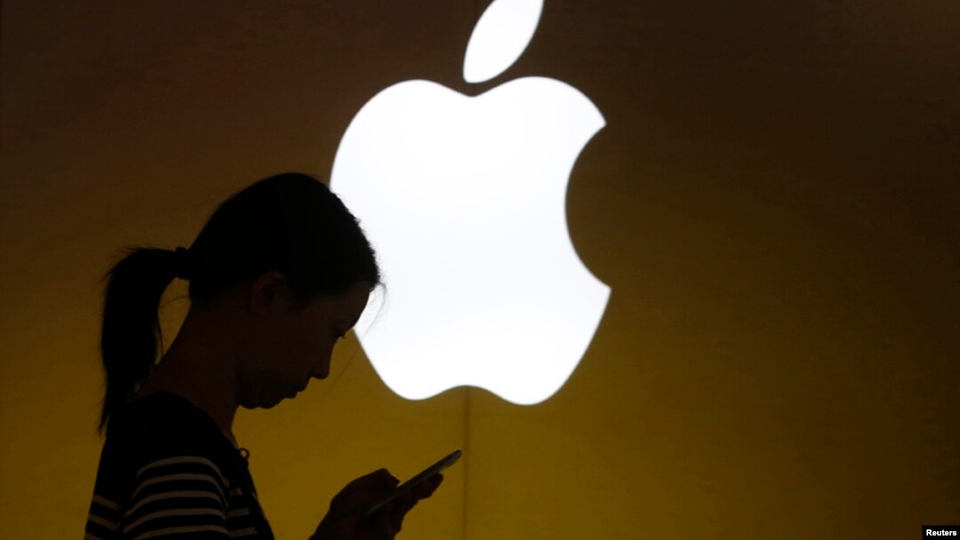 Seorang perempuan sibuk melihat ponselnya di luar toko Apple di pusat kota Shanghai 10 September 2013. (Foto: dok)