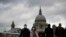 People wearing face masks walk across the Millennium footbridge backdropped by the dome of St Paul's Cathedral in London, March 10, 2020. 