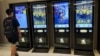 A man checks a ticketing machine next to screens displaying movie posters for the Chinese film "Upstream," at a cinema in Beijing, Aug. 13, 2024. 