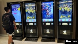 A man checks a ticketing machine next to screens displaying movie posters for the Chinese film "Upstream," at a cinema in Beijing, Aug. 13, 2024. 