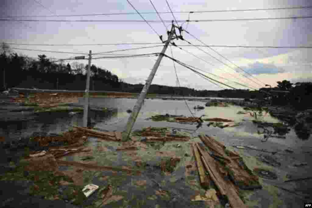 Leaning electric poles are left in the area following massive tsunami triggered by March 11 earthquake in Daigasaki, near Sendai, Miyagi Prefecture, Japan, Monday, March 14, 2011. (AP Photo/Junji Kurokawa)