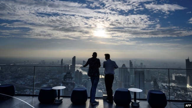 FILE — Two men stand on a terrace of the MahaNakhon building — now known as the King Power Mahanakhon — overlooking Bangkok's skyline, Nov. 11, 2020.