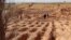 (FILE) Libyans walk around graves dug on the ground from which bodies were recovered in the western town Tarhuna on February 9, 2022.