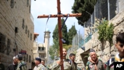 Cristianos de un movimiento de boys scouts, uno llevando una cruz, caminan por la Via Dolorosa hacia la Iglesia del Santo Sepulcro, donde según la tradición fue cruxificado Jesucristo durante el Viernes Santo, el viernes 19 de abril de 2019.