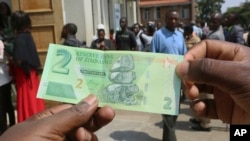 FILE: A man holds one of the new two-dollar banknotes issued by the Reserve Bank of Zimbabwe in Harare, Tuesday, Nov, 12, 2019.